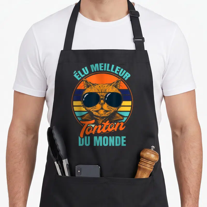 Tablier de cuisine noir avec illustration rétro d'un chat portant des lunettes noires et un texte coloré.