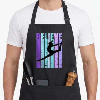 Tablier de cuisine noir avec silhouette gymnaste et texte BELIEVE sur bandes colorées délavées style rétro.