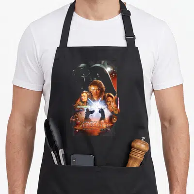 Tablier de cuisine noir avec illustration rétro Star Wars Episode III Revenge of the Sith et personnages au centre.