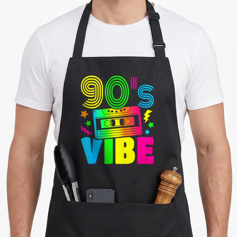 Tablier de cuisine noir avec illustration de cassette audio multicolore et texte 90s Ambiance en lettres géométriques.
