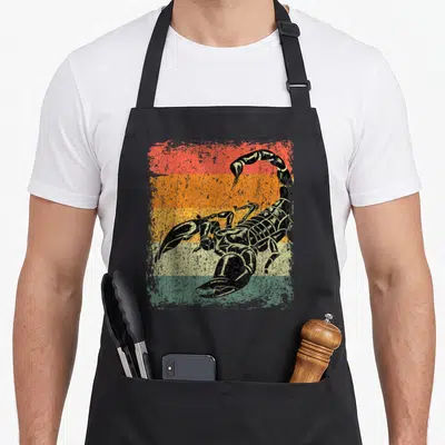 Tablier de cuisine noir avec illustration d'un scorpion noir sur fond de bandes colorées délavées rouge orange jaune vert et beige.