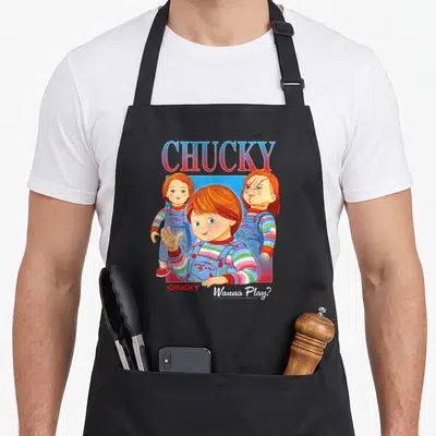 Tablier de cuisine noir avec illustration colorée de Chucky Wanna Play en style vintage années 80.