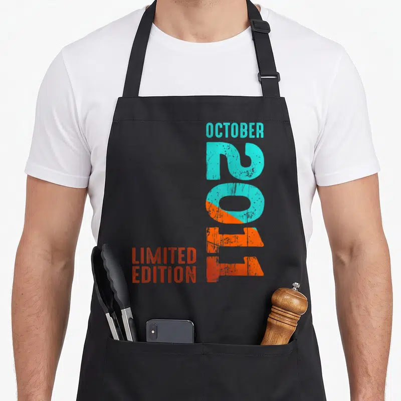 Tablier de cuisine noir avec le texte Octobre 2011 Limited Edition en typographie dégradée turquoise et orange.