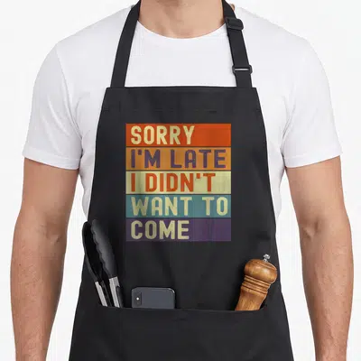 Tablier de cuisine noir avec un motif rectangulaire coloré comportant cinq bandes horizontales et du texte en majuscules.