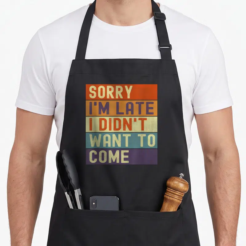 Tablier de cuisine noir avec un motif rectangulaire coloré comportant cinq bandes horizontales et du texte en majuscules.