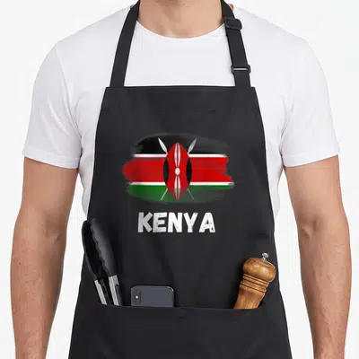 Tablier de cuisine noir avec drapeau Kenya Pride stylisé en brushstroke et le mot Kenya en blanc texturé.