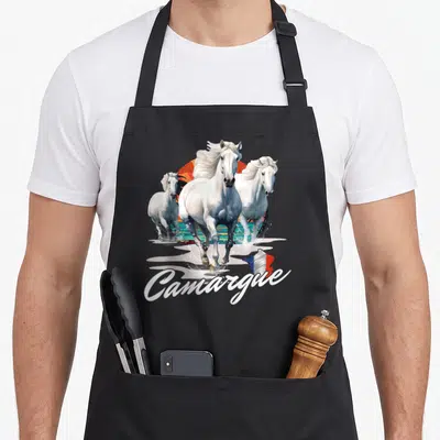 Tablier de cuisine noir avec illustration de trois chevaux blancs de Camargue et le mot Camargue en blanc.