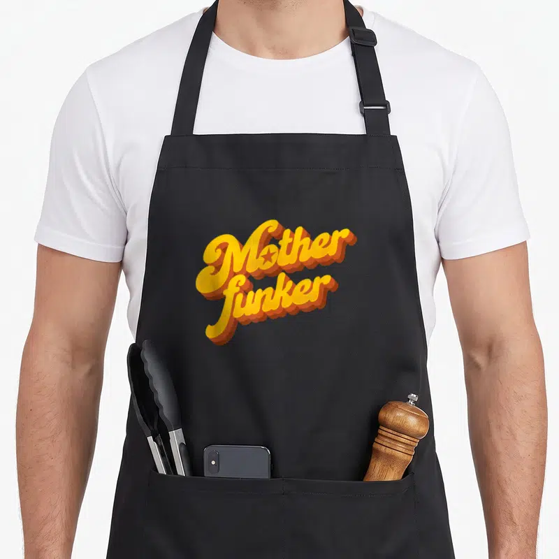 Tablier de cuisine noir avec l'inscription Motherfunker en lettres jaunes et oranges style funk rétro.