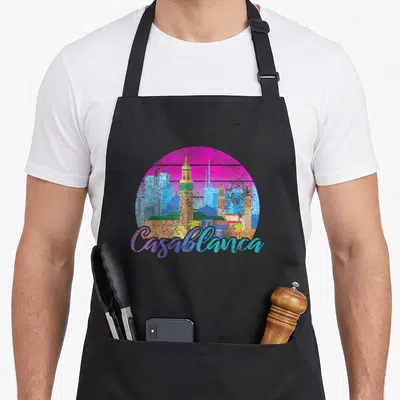 Tablier de cuisine noir avec illustration circulaire du skyline de Casablanca en couleurs vives et texte script gratuit.