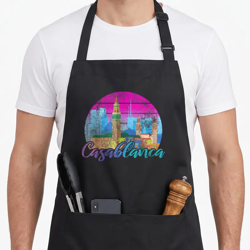 Tablier de cuisine noir avec illustration circulaire du skyline de Casablanca en couleurs vives et texte script gratuit.