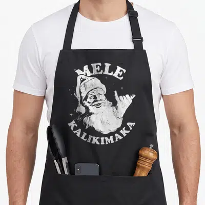 Tablier de cuisine noir avec illustration blanche d'un Père Noël faisant le signe shaka et les mots Mele Kalikimaka.