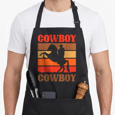 Tablier de cuisine noir avec silhouette de cow-boy sur fond de bandes orange et jaune rétro.
