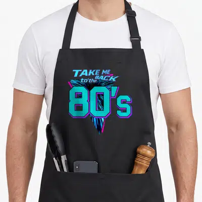 Tablier de cuisine noir avec l'inscription Take Me Back to the 80s en lettres turquoise et magenta sur fond géométrique.