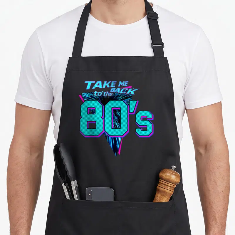 Tablier de cuisine noir avec l'inscription Take Me Back to the 80s en lettres turquoise et magenta sur fond géométrique.