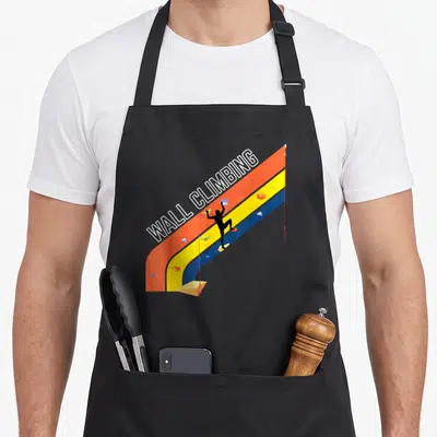 Tablier de cuisine noir avec une paroi d'escalade colorée orange jaune et bleue et un grimpeur en silhouette noire.