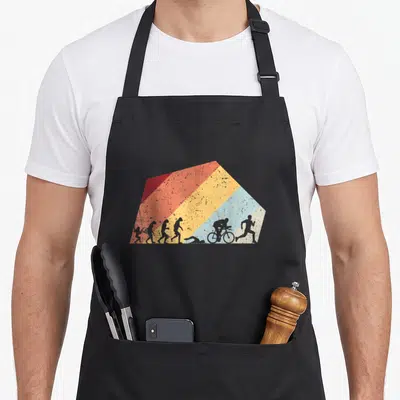 Tablier de cuisine noir avec illustration rétro montrant l'évolution en nage, vélo et course sur bandes de couleur diagonales.