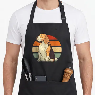 Tablier de cuisine noir avec illustration d'un beagle assis devant un soleil rétro multicolore aux teintes orange, jaune et vert.