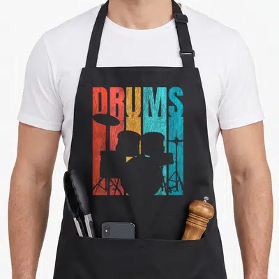 Tablier de cuisine noir avec motif Drums rétro coloré et silhouettes de batterie crackelées.