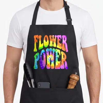 Tablier de cuisine noir avec l'inscription Flower Power en lettres tie-dye aux couleurs vives du arc-en-ciel et effet batik spiral.