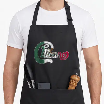 Tablier de cuisine noir avec l'inscription Chicano en lettres cursives aux couleurs vert blanc et rouge du Mexique.