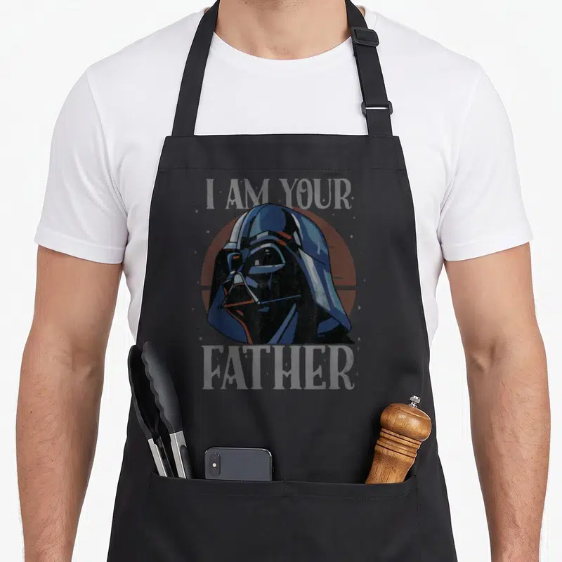 Tablier de cuisine noir avec illustration rétro du casque de Dark Vador et texte I Am Your Father en arrière-plan.