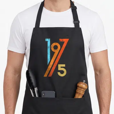 Tablier de cuisine noir avec l'inscription 1975 aux couleurs vives et effet vieilli