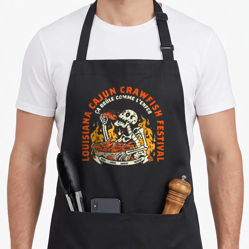 Tablier de cuisine noir avec illustration rétro d'un squelette tenant une écrevisse devant un feu et un bol de crustacés.
