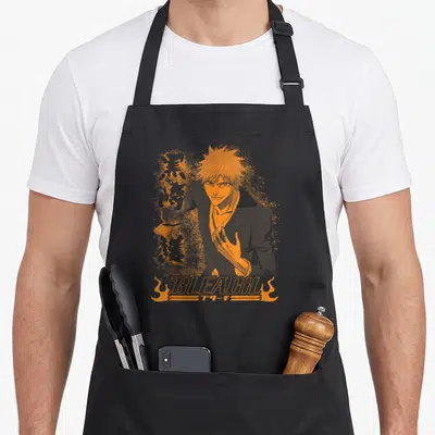 Tablier de cuisine noir avec illustration orange d'Ichigo Kurosaki et le logo Bleach en bas.