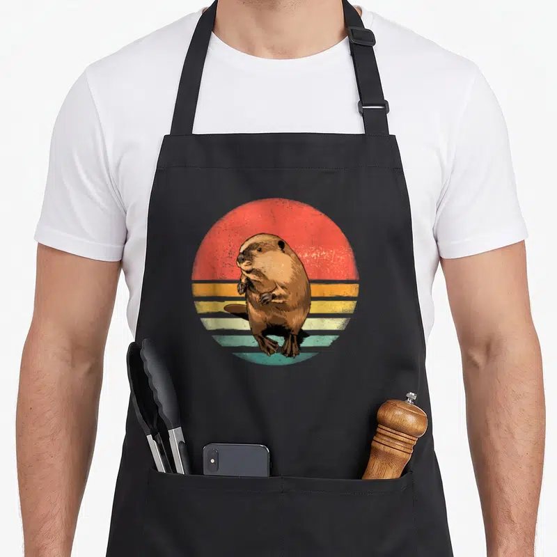 Tablier de cuisine noir avec illustration d'un castor brown sur fond de soleil rétro multicolore.