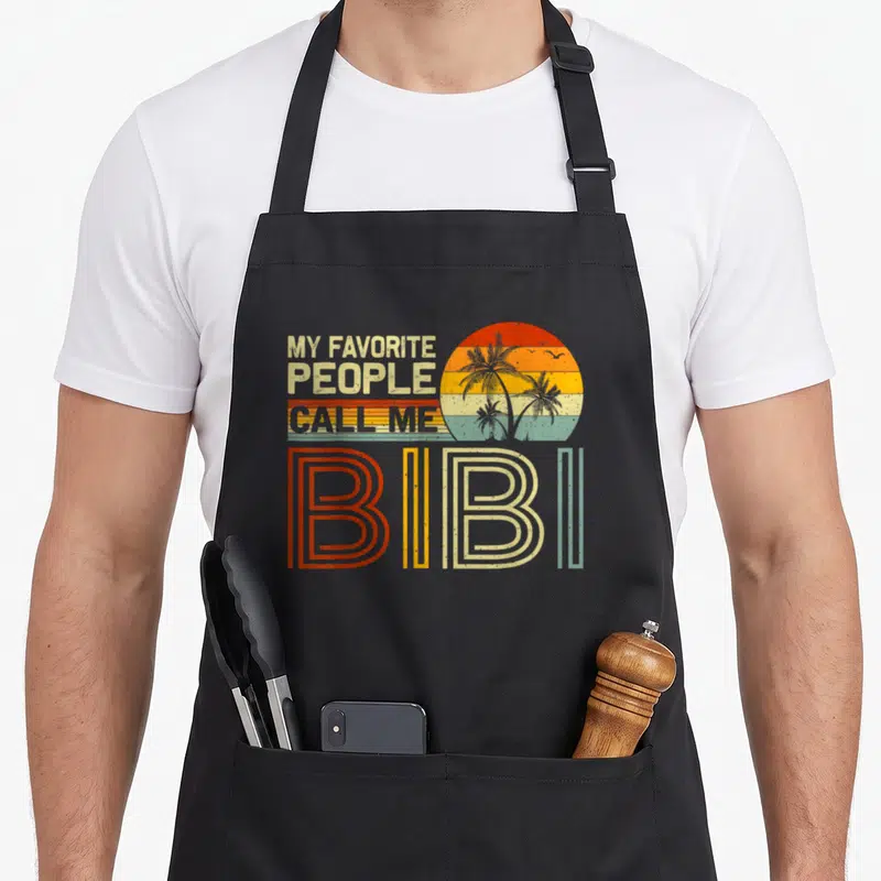 Tablier de cuisine noir avec motif rétro My Favorite Gens Call Me Bibi et soleil aux palmiers.