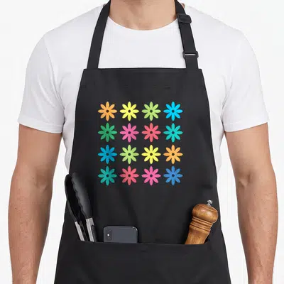 Tablier de cuisine noir avec un motif de fleurs rétro multicolores disposées en grille sur fond uni.