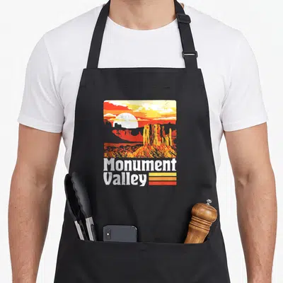 Tablier de cuisine noir avec illustration colorée de Monument Valley et texte blanc style années 80