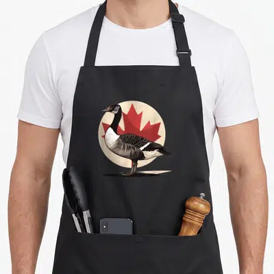 Tablier de cuisine noir avec illustration d'une oie canadienne devant une feuille d'érable rouge circulaire.
