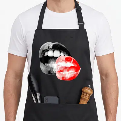 Tablier de cuisine noir avec deux lèvres stylisées en noir et rose vif superposées au centre.