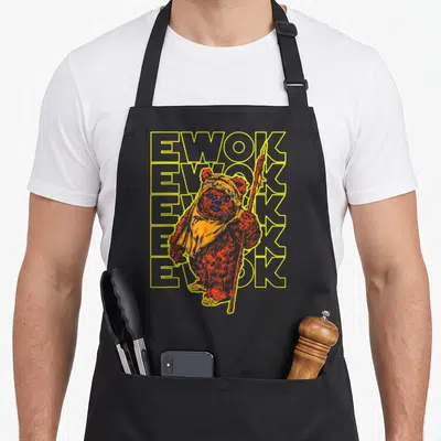 Tablier de cuisine noir avec illustration Ewok style halftone et texte Ewok répété en jaune.
