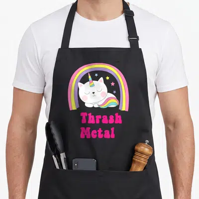 Tablier de cuisine noir avec licorne blanche, arc-en-ciel et texte Thrash Metal rose vif.