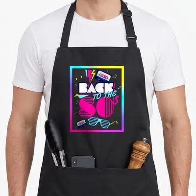 Tablier de cuisine noir avec motif graphique rétro Back to the 80's cassettes et lunettes.
