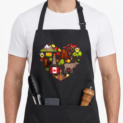 Tablier de cuisine noir avec un motif en cœur regroupant des symboles du Canada comme le drapeau, la feuille d'érable et l'orignal.