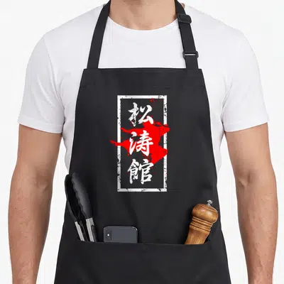 Tablier de cuisine noir avec calligraphie japonaise blanche et tache rouge style vintage dans un cadre rectangulaire blanc.