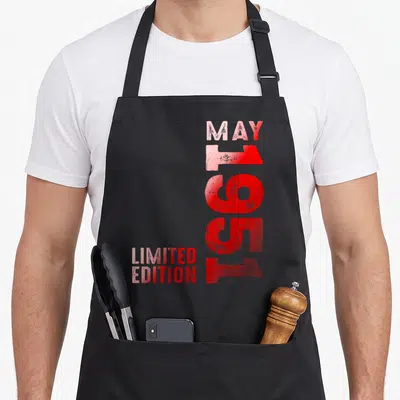 Tablier de cuisine noir avec typographie verticale rouge indiquant Mai 1951 Limited Edition sur fond uni.