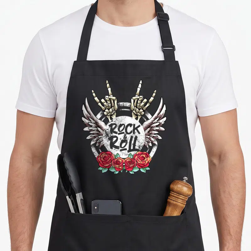 Tablier de cuisine noir avec deux mains squelettiques, des ailes et des roses rouges autour du texte Rock & Roll.