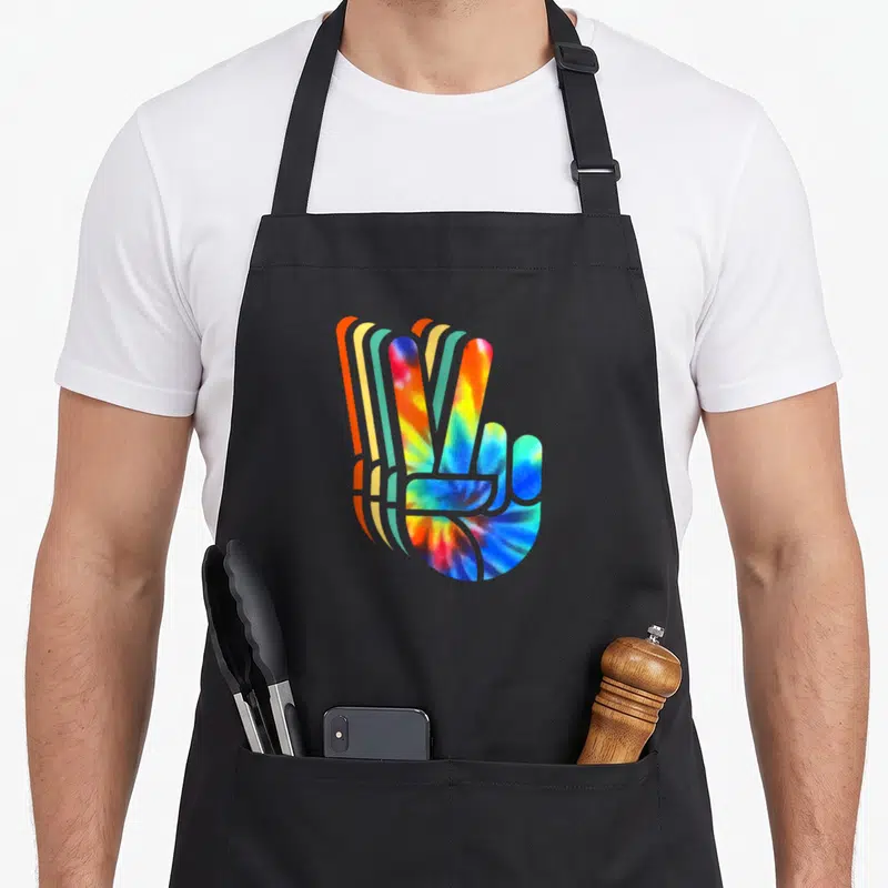 Tablier de cuisine noir avec main signe de la paix en tie dye multicolore style rétro.