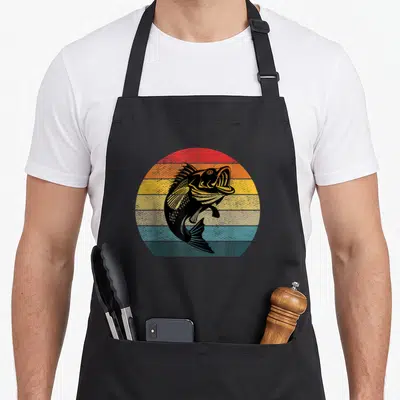 Tablier de cuisine noir avec illustration circulaire d'un poisson sautant sur fond de bandes colorées délavées style rétro.
