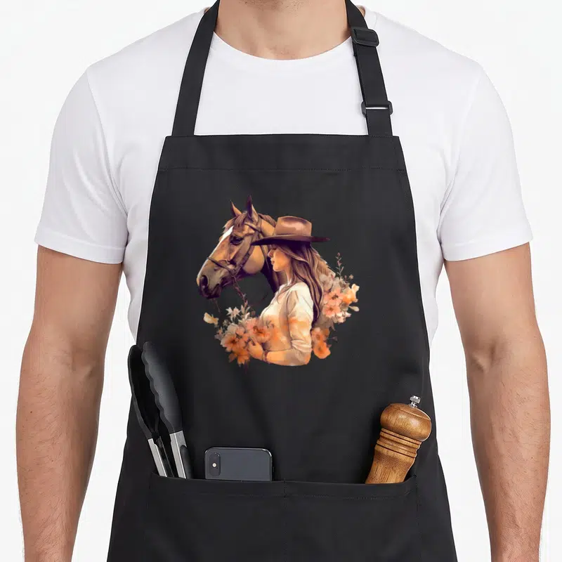 Tablier de cuisine noir avec illustration d'une cavalière au chapeau rétro et de fleurs oranges.