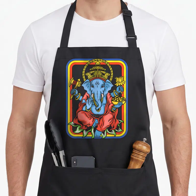 Tablier de cuisine noir avec une illustration colorée du dieu Ganesha assis en tailleur dans un cadre rectangulaire aux contours vifs.