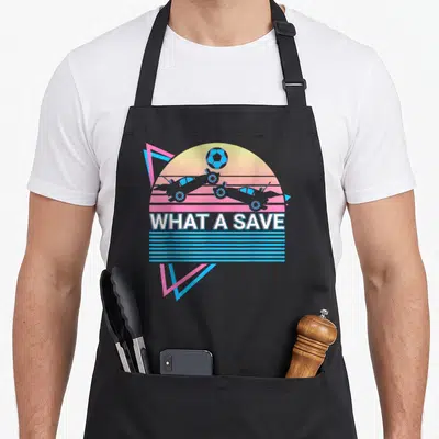 Tablier de cuisine noir avec illustration rétro de voitures télécommandées et texte What A Save sous un soleil pastel.