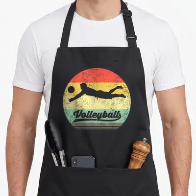 Tablier de cuisine noir avec illustration circulaire retro d'un joueur de beachvolley et le mot Volleyball en typographie ancienne.