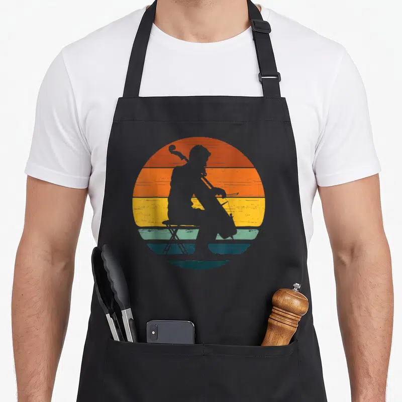 Tablier de cuisine noir avec silhouette de contrebassiste assis devant un soleil couchant coloré style rétro