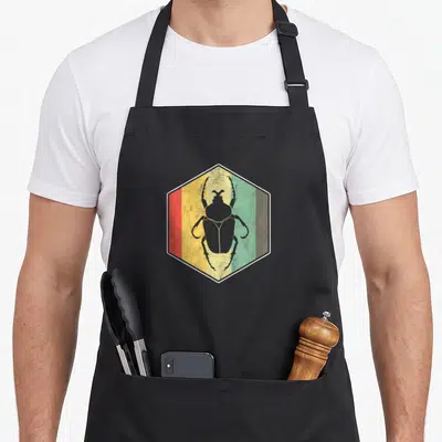 Tablier de cuisine noir avec illustration hexagonale d'un insecte aux couleurs jaune, vert et rouge sur fond texturé.