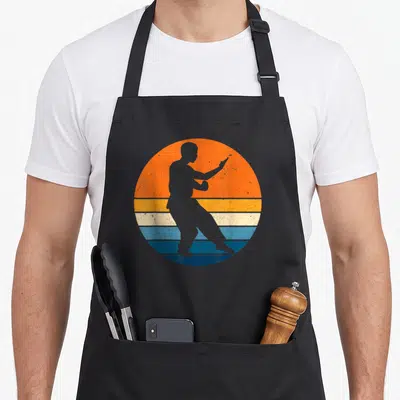 Tablier de cuisine noir avec silhouette Wing Chun sur fond sunset orange et bandes bleues rétro